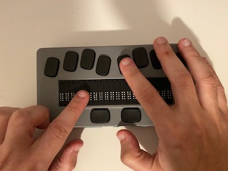 La foto presenta unos dedos tocando la línea Braille y el teclado tipo Perkins. Foto de la línea Braille Chameleon 20.