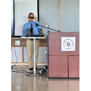 La foto muestra a Manolo al lado del podio durante su presentación.