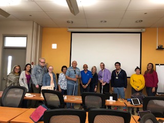 La foto muestra a Manolo posando con estudiantes ciegos durante su charla en la UPR Aguadilla. Foto de Manolo junto a participantes de la charla.