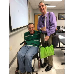 La imagen muestra al Dr. Irmo Marini en una silla de ruedas posando junto con Manolo que está sujetando su bastón blanco.