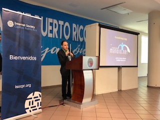 La foto muestra a Manolo ofreciendo la charla desde el podio. Foto de Manolo ofreciendo charla en evento Enamórate del Internet.