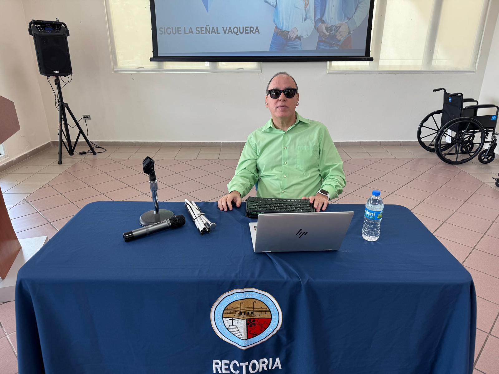 La foto muestra a Manolo junto con personal del Internet Society de Puerto Rico y el Rector de la UPR Bayamón. Foto de Manolo detrás de su computadora como parte de la charla.