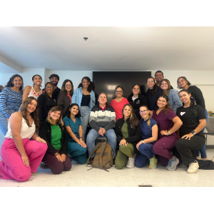 La foto presenta a Manolo sentado en el centro de un grupo de estudiantes de terapia ocupacional. Hay estudiantes que están de pie y otros de rodillas posando para la foto.