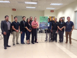 La foto muestra a Manolo junto a varios miembros de la Asociación de Estudiantes de Programación InterDev. En el centro de la foto, aparece el cartel con el logo de la asociación que reúne a estudiantes de la Universidad Interamericana de Bayamón. Foto de Manolo junto a estudiantes universitarios miembros de InterDev.