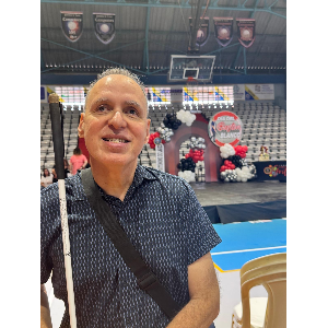 Foto de Manolo posando frente al cartel del evento Día Internacional del Bastón Blanco.