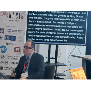 La foto muestra a Manolo posando al lado del cartel de la Conferencia NASIG 2023.