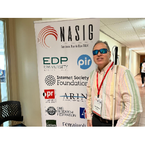La foto muestra a Manolo junto al cartel NASIG 2024.