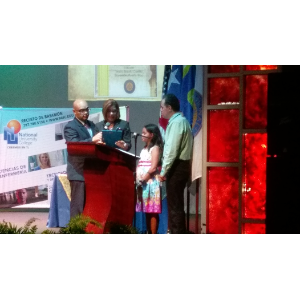 La foto muestra a Manolo junto con su hija Ámbar como parte del mensaje en la ceremonia al lado del podio.