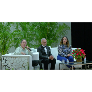 La foto muestra a Manolo junto a otros dos panelistas sentados en un sofá en la tarima del anfiteatro.
