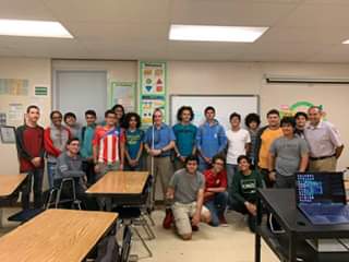 Manolo se encuentra de pie sujetando su bastón blanco. Foto de Manolo junto a estudiantes del grado 10 de la Escuela Superior de la Universidad de Puerto Rico (UPR).