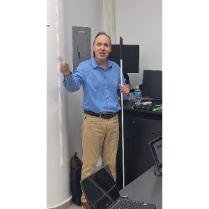 Foto de Manolo utilizando su computadora con una línea Braille mientras ofrece el taller.